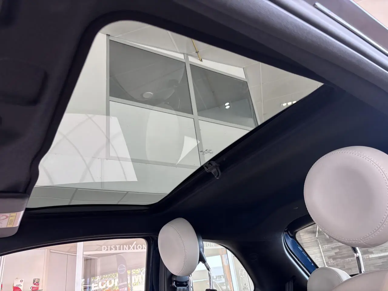 Vue intérieure du toit vitré panoramique fixe de la Fiat 500 vert, avec appuie-têtes avant gris clair visibles.