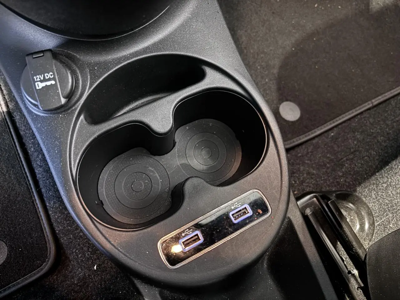 Gros plan sur la console centrale avec porte-gobelets et deux ports USB de la Fiat 500 verte de 2021.