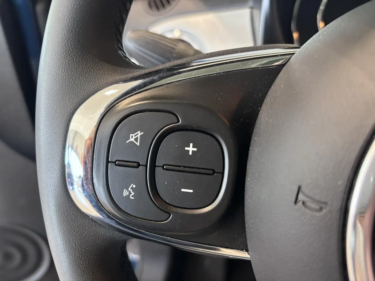 Gros plan sur les commandes de volume et de coupure du son au volant de la Fiat 500, finition Dolcevita.