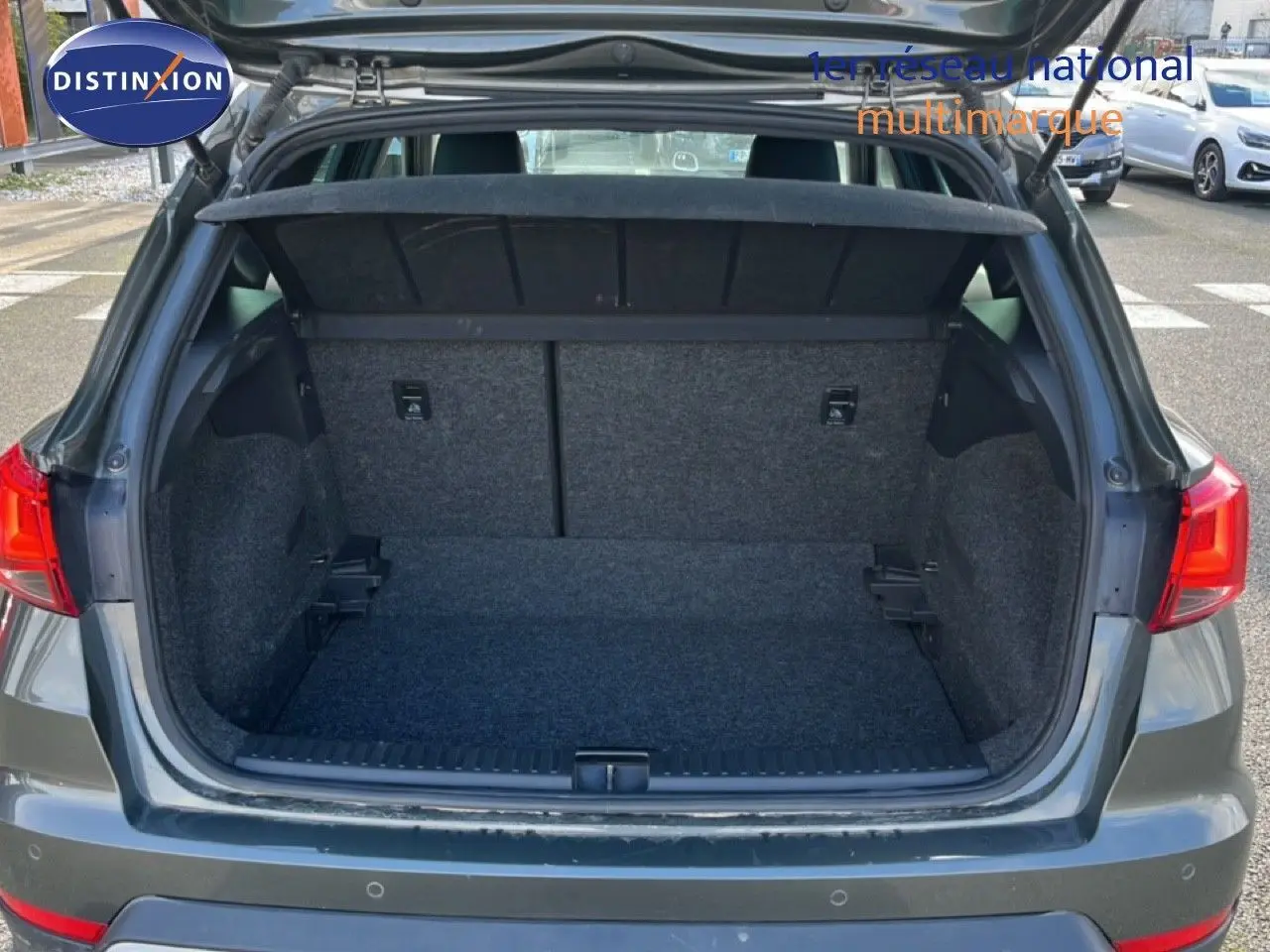 Coffre ouvert vu de l'arrière d'un SEAT Arona gris métallique, montrant un espace de chargement vide et propre.