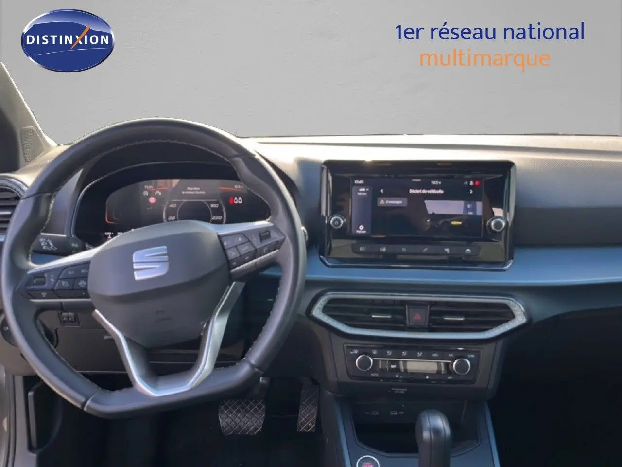 Vue intérieure du tableau de bord et volant noir du SEAT Arona gris magnétique, avec écran tactile central et commandes au volant.
