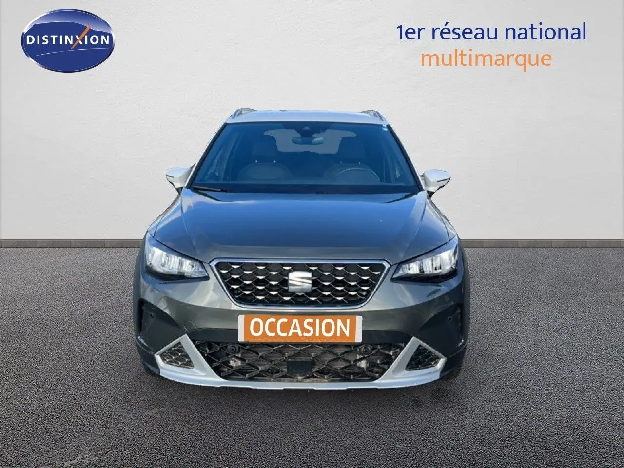 Vue frontale d'un SEAT Arona gris magnétique avec calandre noire et détails argentés, plaque "OCCASION" visible.