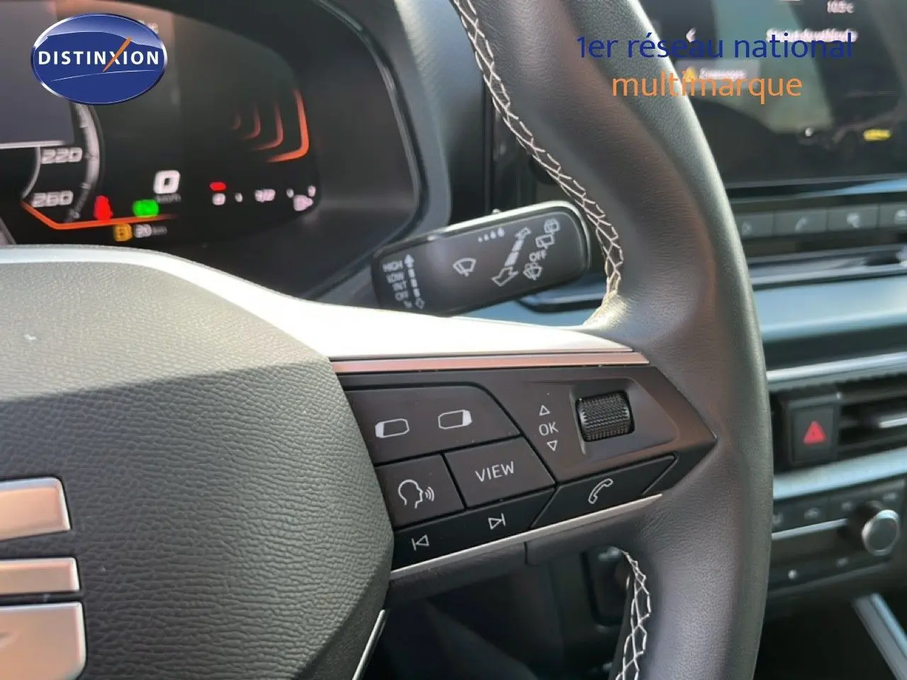 Gros plan sur le volant cuir noir à surpiqûres blanches du SEAT Arona 2025 avec commandes multifonctions et tableau de bord numérique.