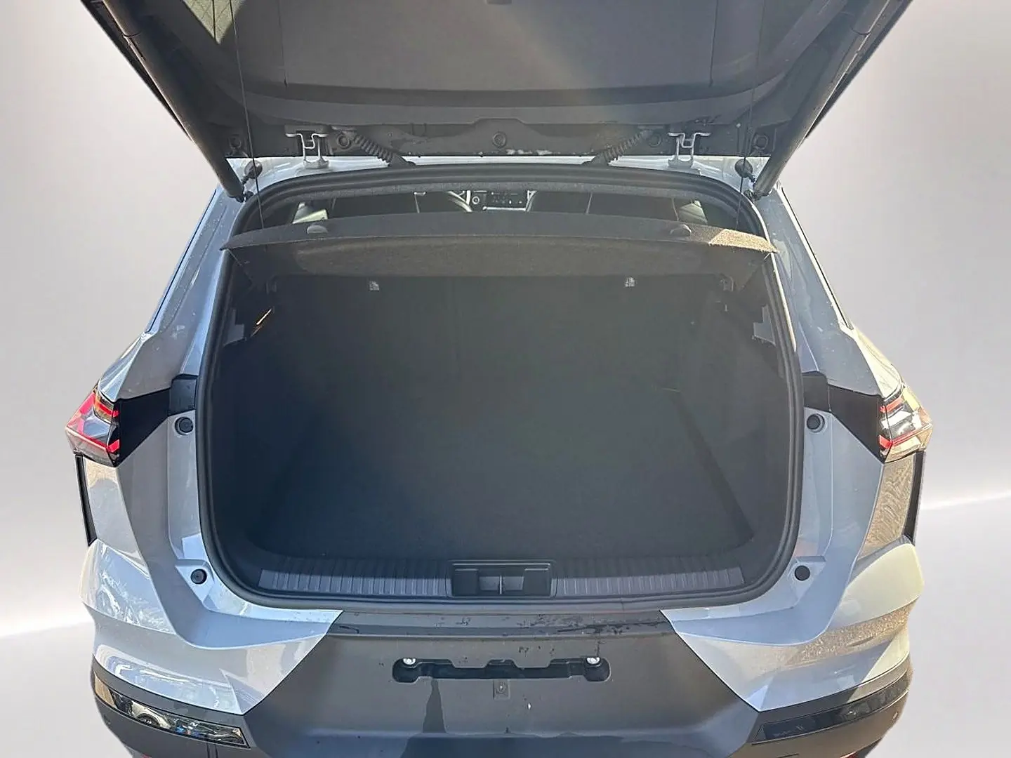 Vue arrière du coffre ouvert du Renault Symbioz gris rafale, soulignant ses lignes modernes et feux arrière LED.