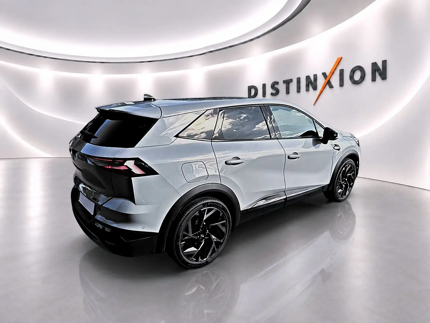 Vue 3/4 arrière droite du Renault Symbioz gris rafale avec jantes noires et toit noir dans un showroom lumineux.