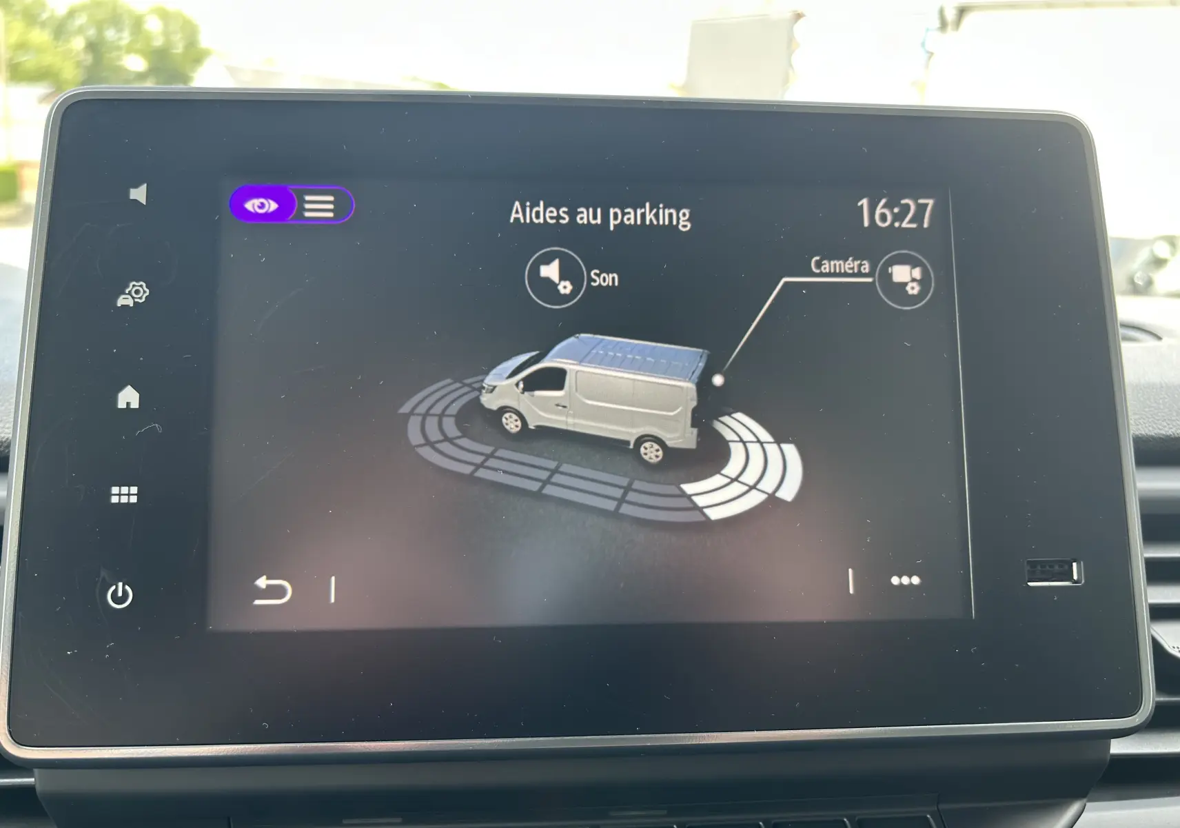Écran tactile intérieur montrant l'aide au parking du Renault Trafic fourgon blanc en vue latérale droite.