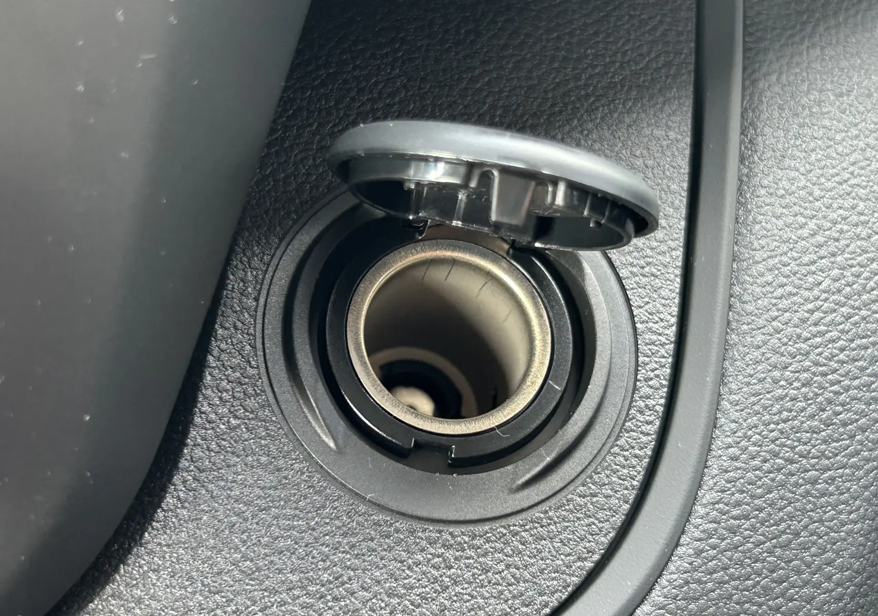 Gros plan sur la prise allume-cigare noire intégrée dans la console intérieure du Renault Trafic Fourgon blanc.