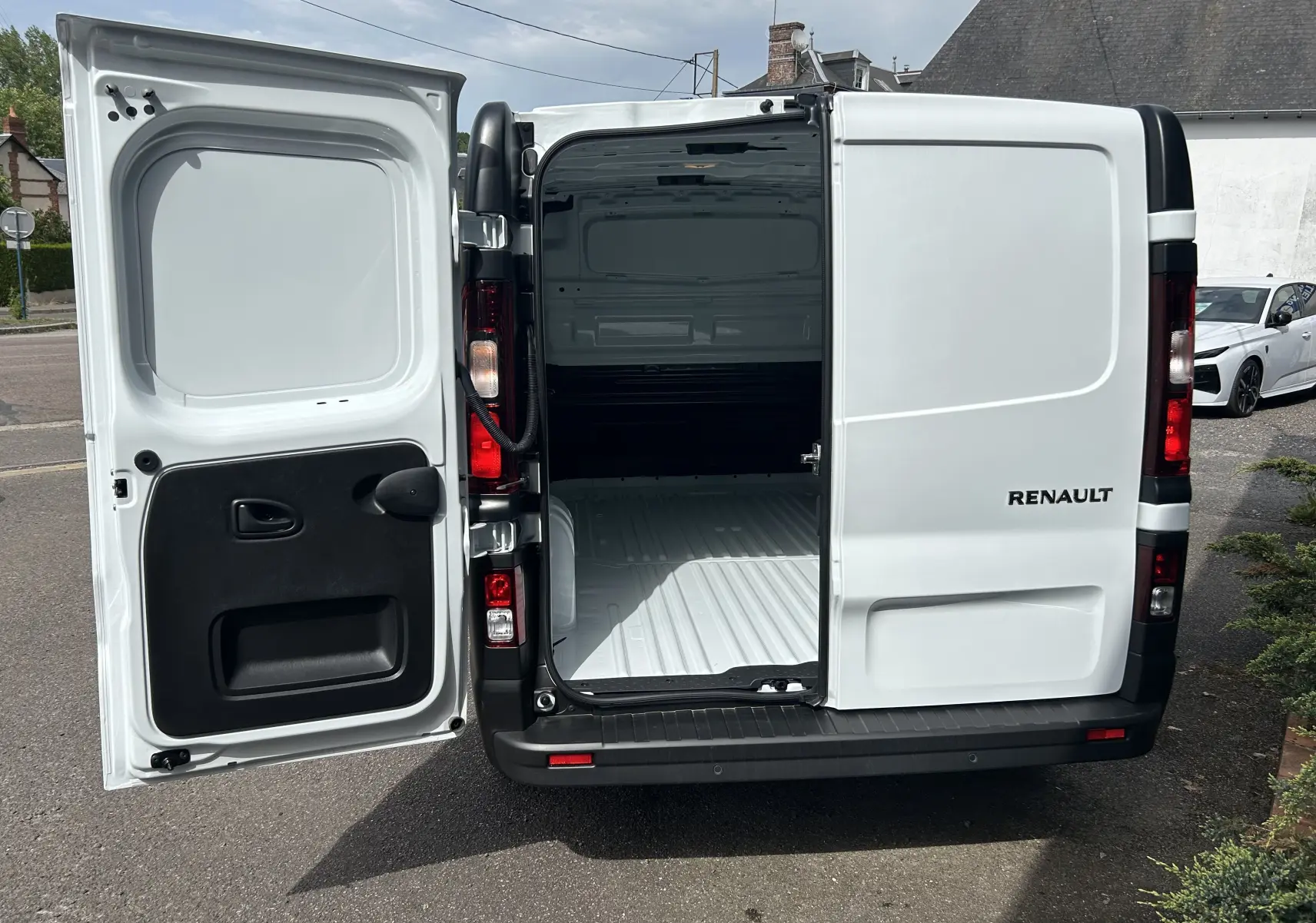 Vue arrière du Renault Trafic blanc avec portes battantes ouvertes montrant l’espace de chargement vide.