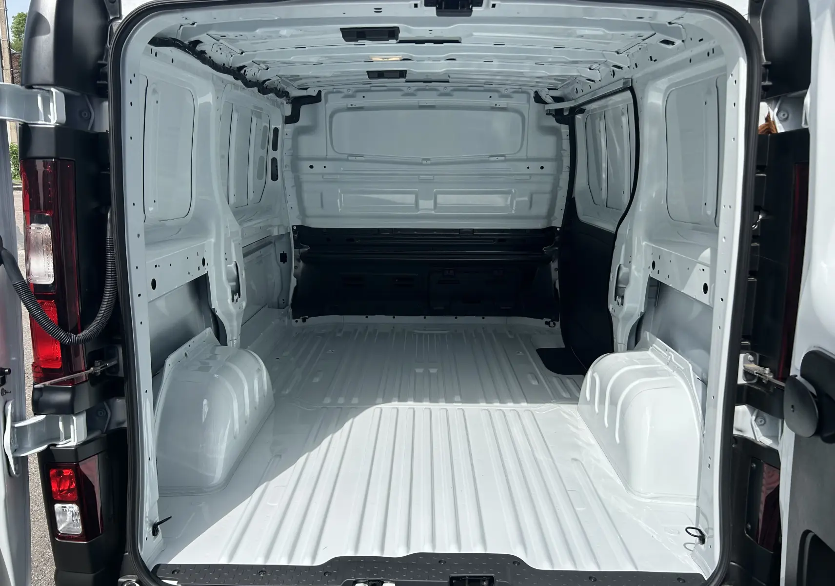 Vue arrière intérieure du fourgon blanc Renault Trafic L1H1 2026, montrant la grande zone de chargement vide et métallique.