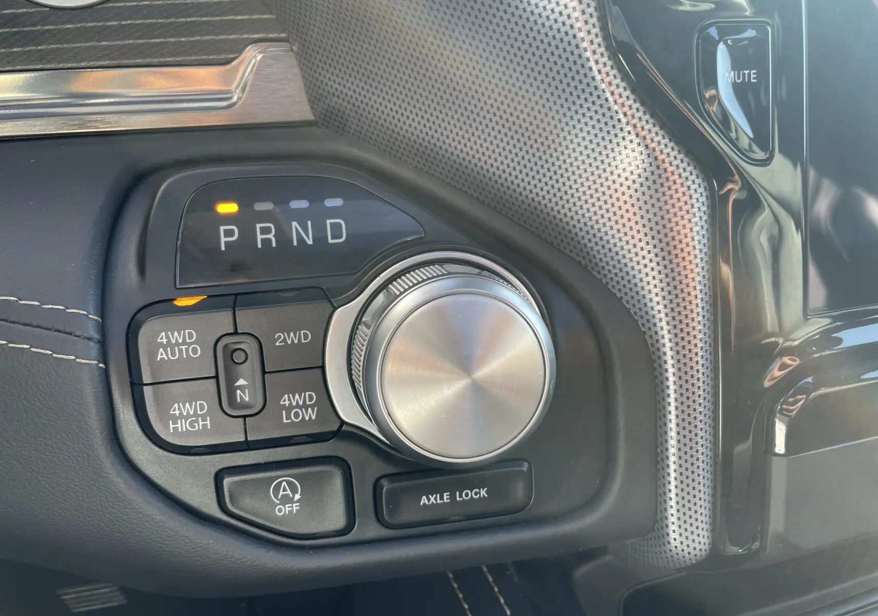 Gros plan sur la commande rotative de boîte automatique et sélecteur 4x4 du Dodge RAM 1500 blanc nacré, intérieur noir.