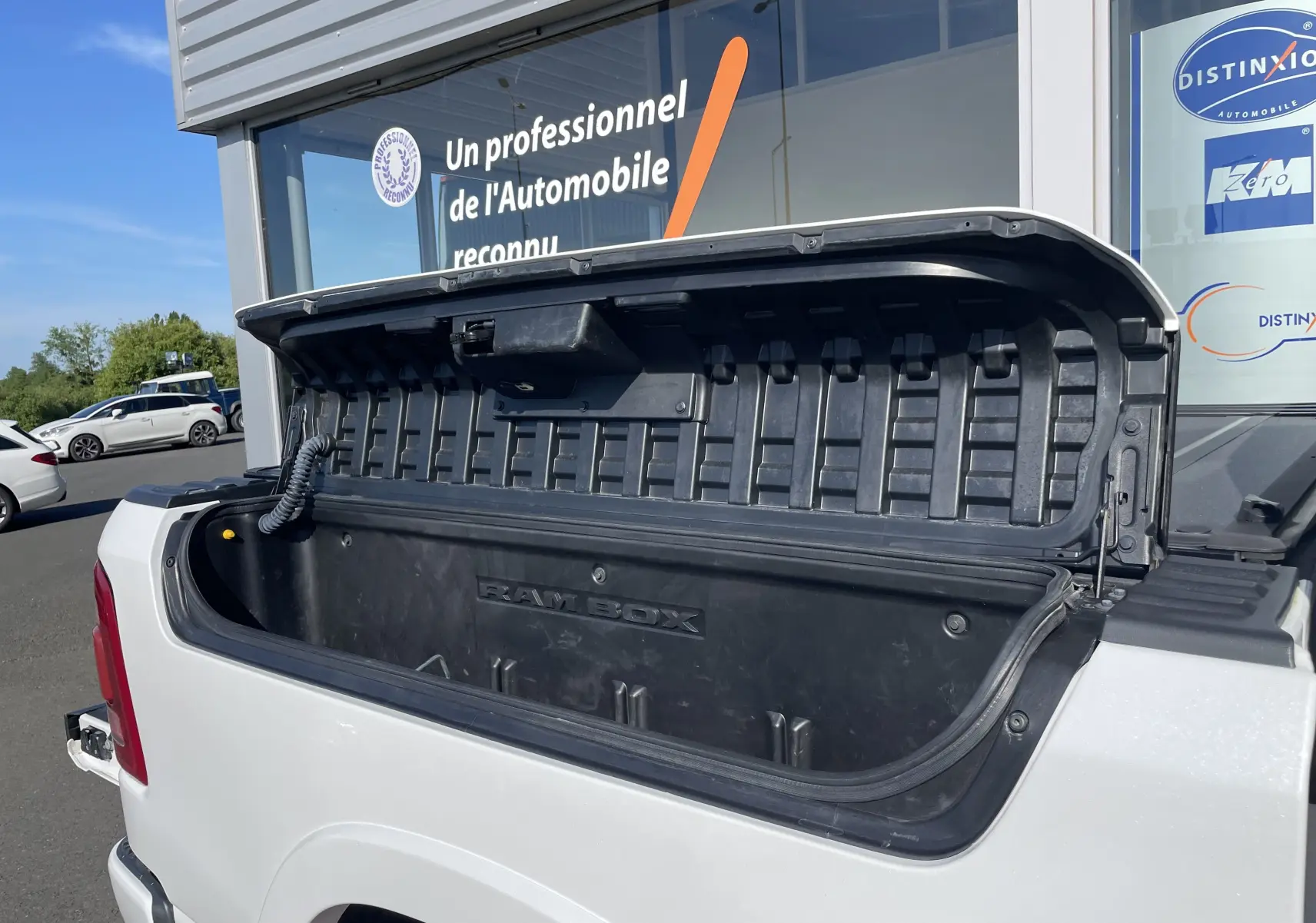 Coffre de rangement RAMBOX ouvert à l'arrière d'un Dodge RAM 1500 blanc nacré, vue côté gauche arrière.