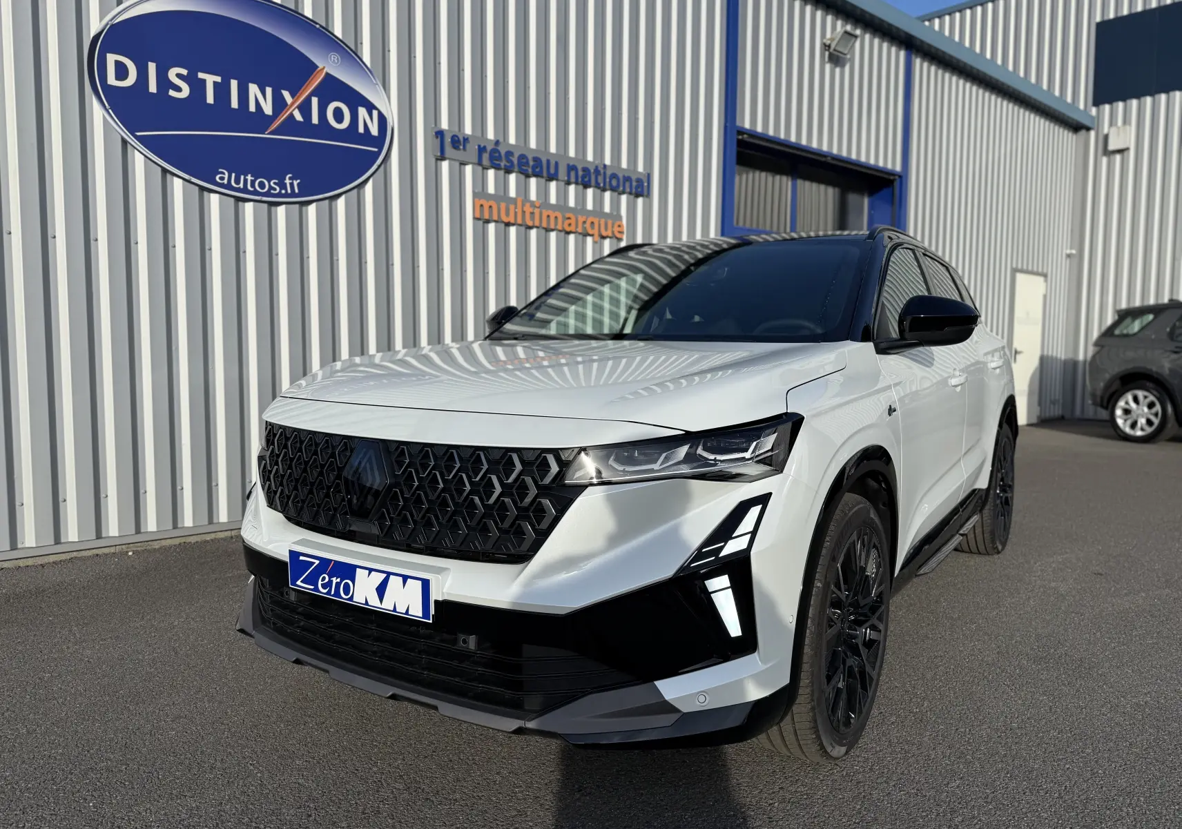 Renault Austral blanc nacré avec toit noir, vue 3/4 avant droit, calandre noire et phares LED distinctifs.