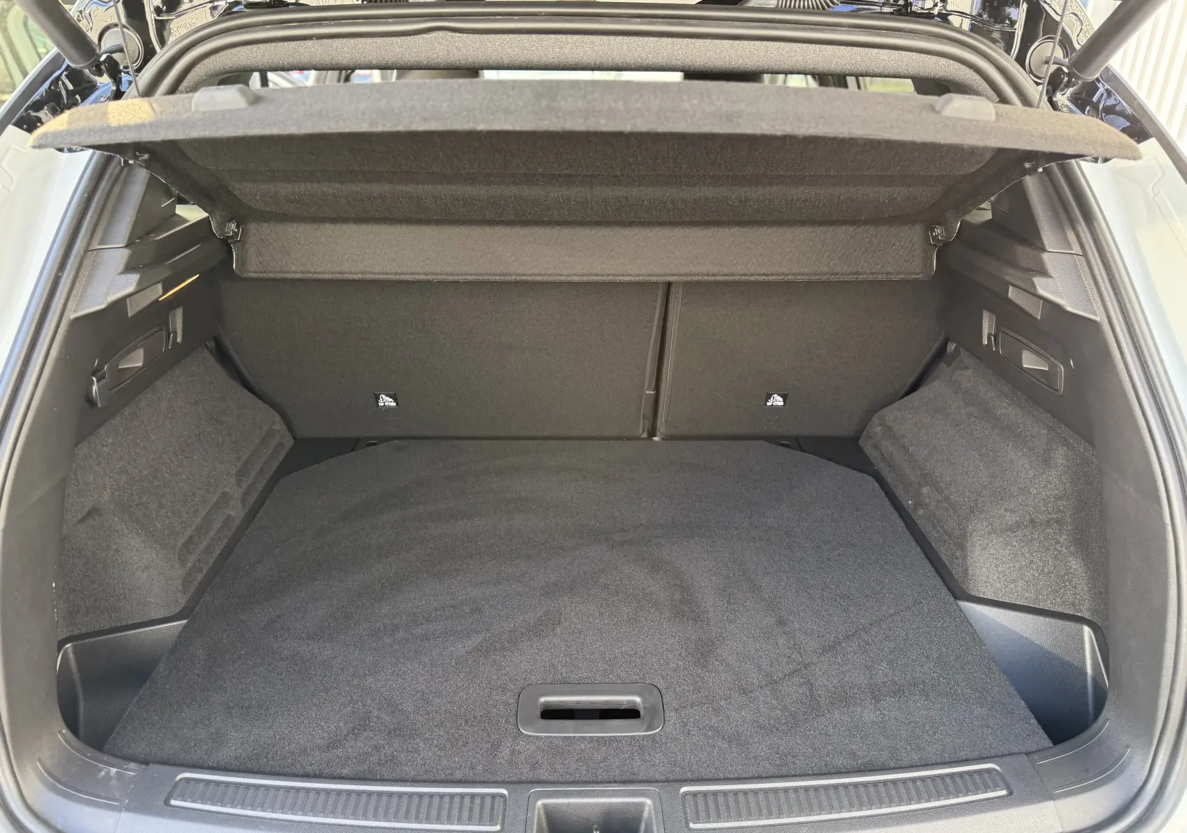 Coffre ouvert vu de l'arrière d'un Renault Austral 2025 blanc nacré avec toit noir, intérieur de coffre noir vide.