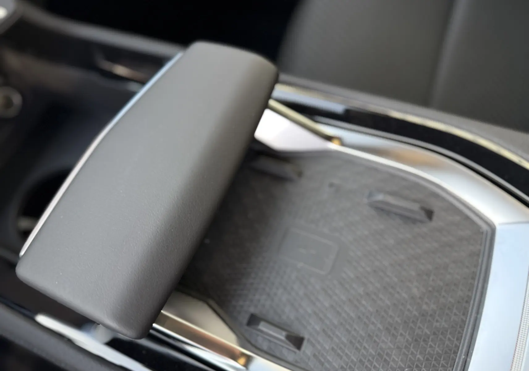 Détail de la console centrale avec accoudoir en cuir gris et surface de recharge sans fil du Renault Austral 2025.