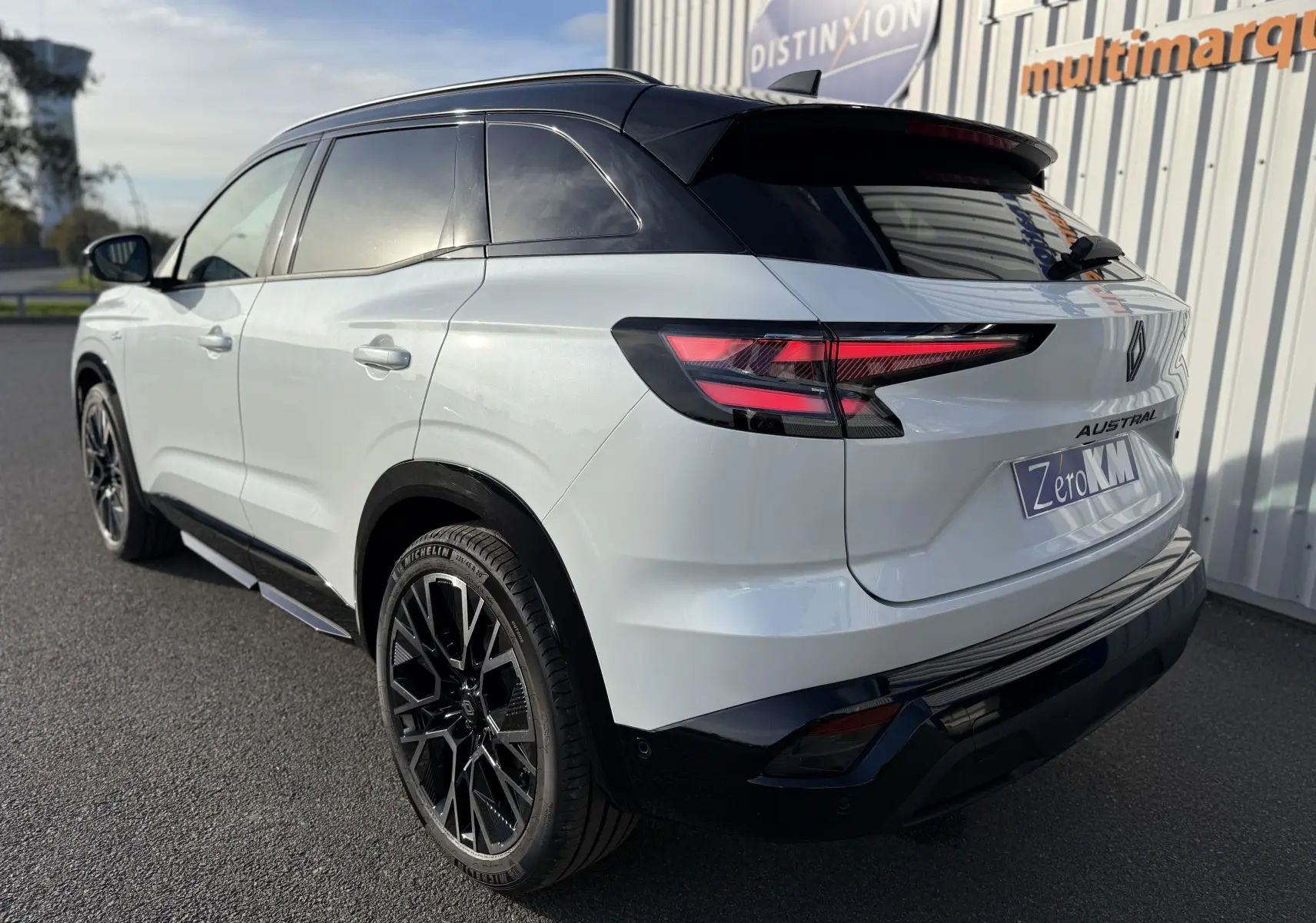 Vue 3/4 arrière droite du Renault Austral blanc nacré avec toit noir, jantes noires et feux arrière LED distinctifs.