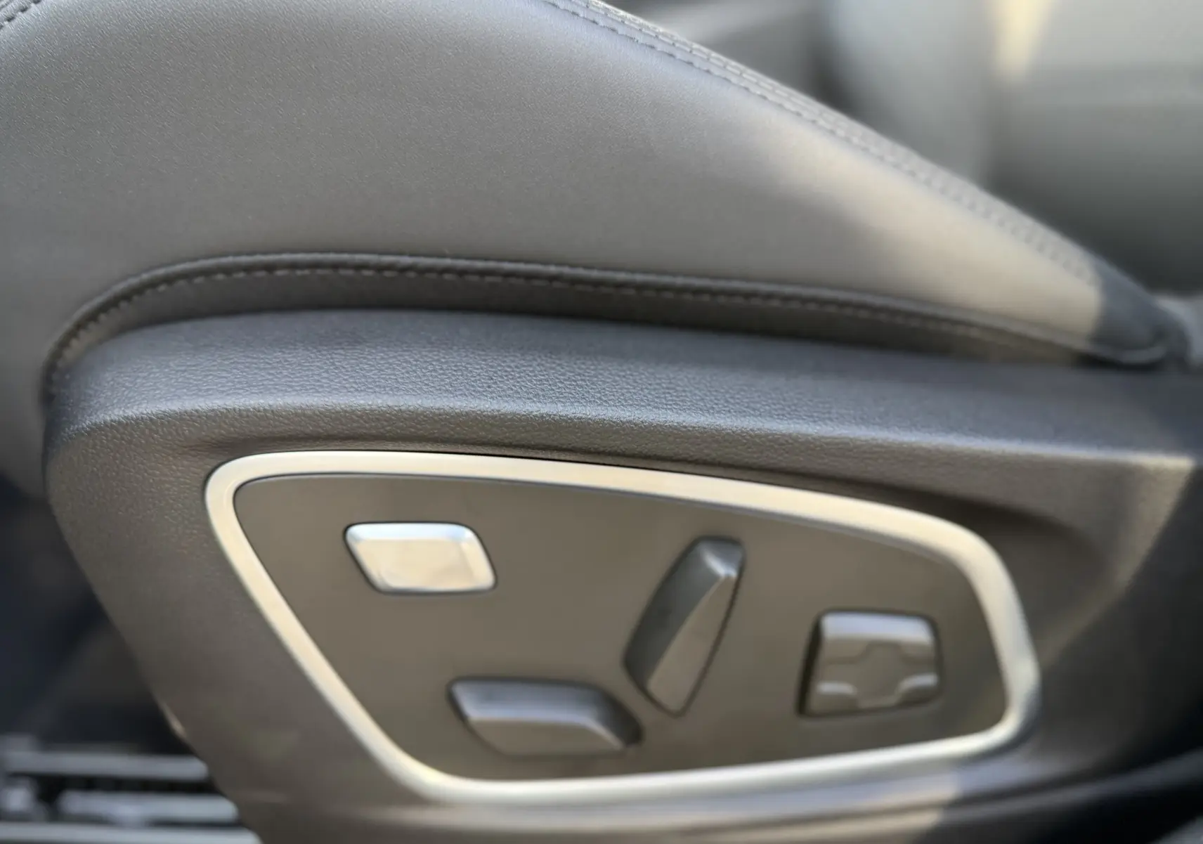 Gros plan sur les commandes de réglage électrique du siège avant en cuir noir du Renault Austral 2025.