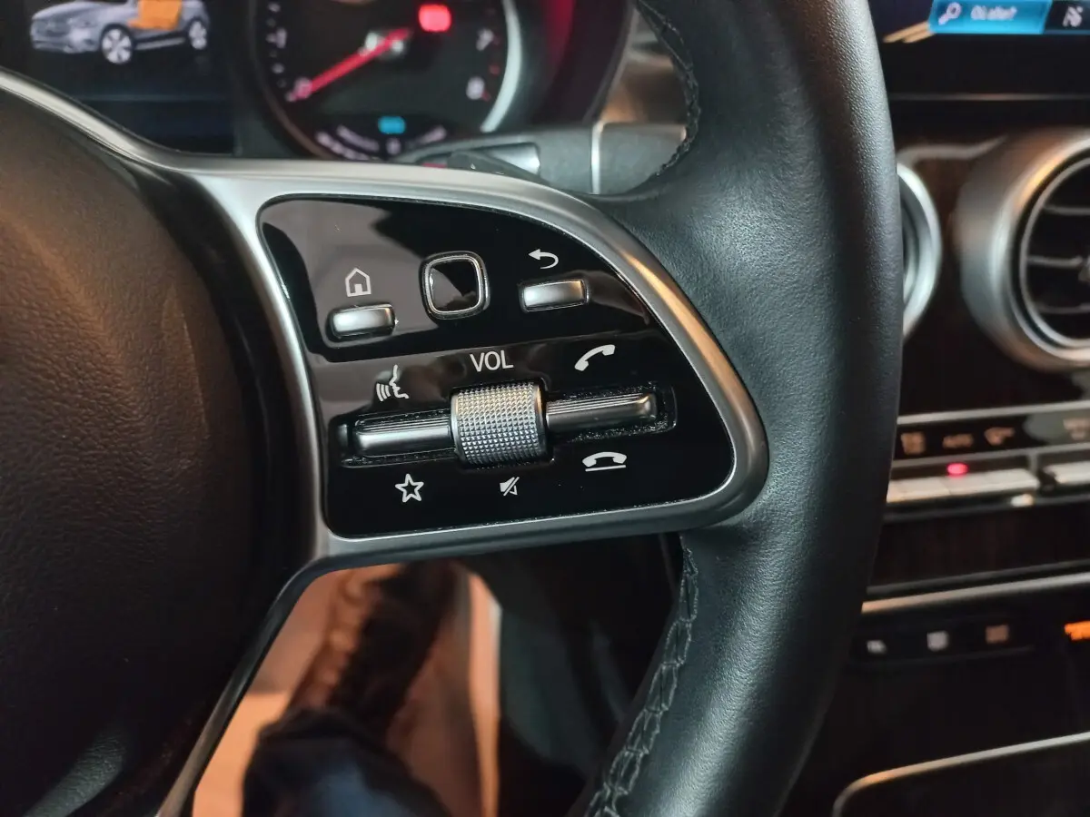 Gros plan sur les commandes du volant côté gauche du Mercedes GLC 300 E Business Line noir, tableau de bord en arrière-plan.