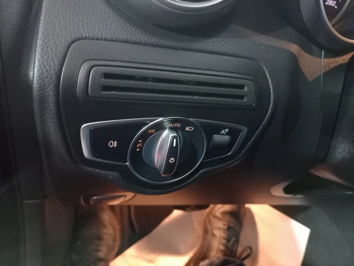 Gros plan sur la commande d'éclairage noire et chrome côté gauche du tableau de bord du Mercedes GLC 300 E noir.