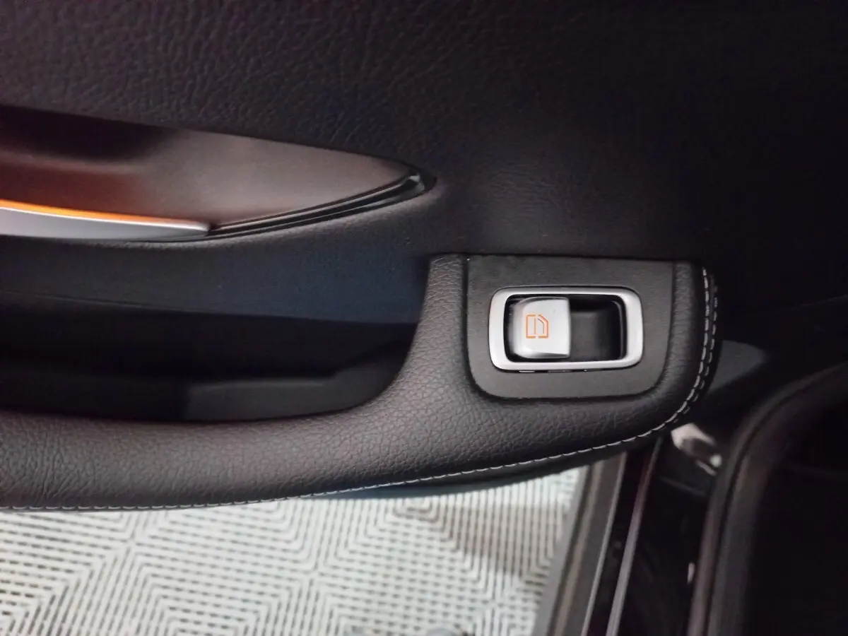 Gros plan sur la poignée intérieure noire avec bouton de déverrouillage orange du côté gauche d'un Mercedes GLC 300 E Business Line 2021.