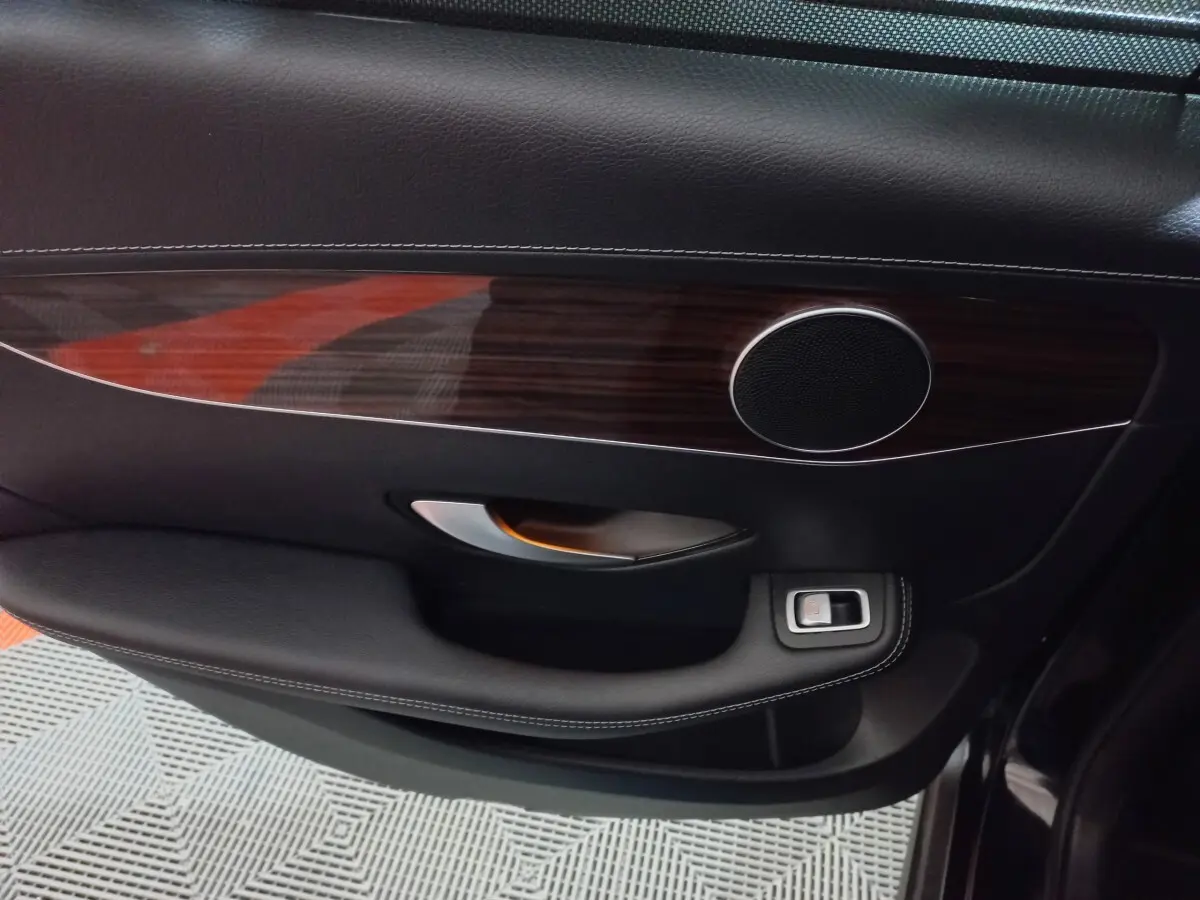 Gros plan sur la garniture intérieure noire et bois foncé de la porte côté gauche du Mercedes GLC 300 E Business Line 2021.