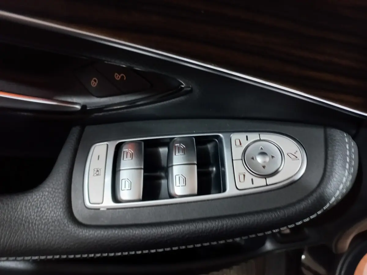 Gros plan sur les commandes de lève-vitres et rétroviseurs côté gauche d'une Mercedes GLC noire, finition Business Line.