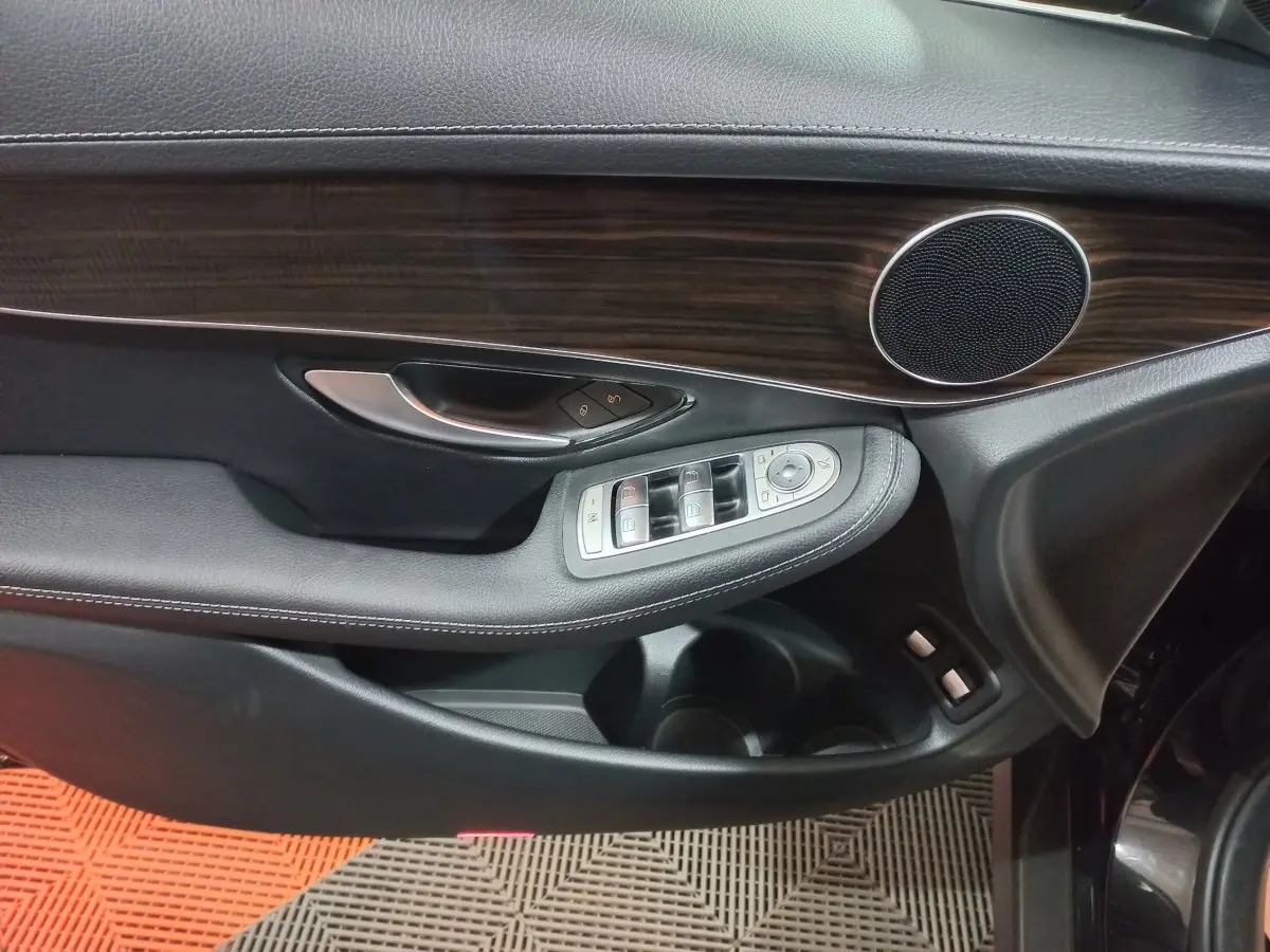 Détail de la porte côté gauche noire du Mercedes GLC 300 E avec insert bois et commandes de vitres et rétroviseurs.