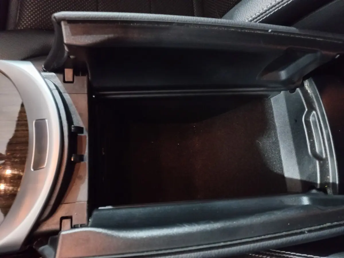 Vue rapprochée de la console centrale noire ouverte du Mercedes GLC 300 E Business Line 2021, intérieur cuir.