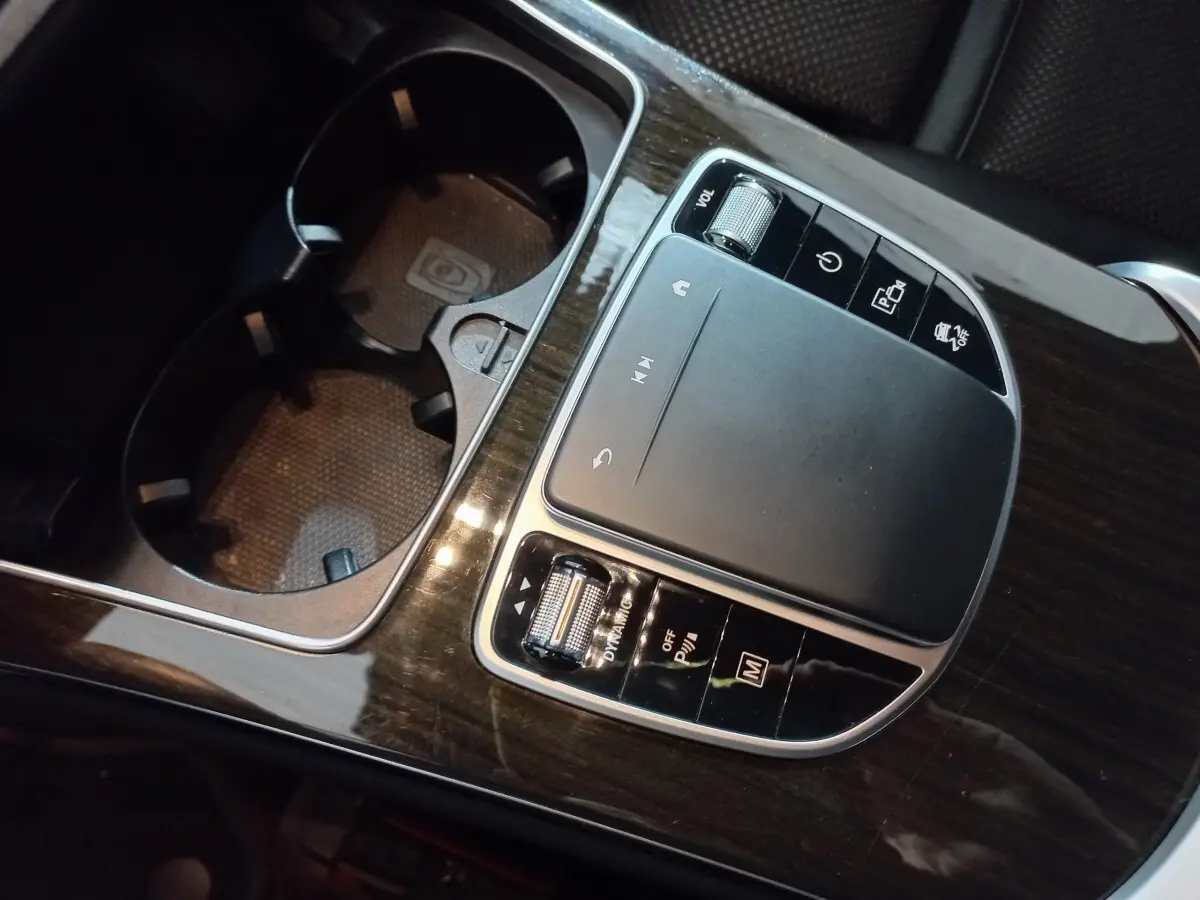 Gros plan sur la console centrale en bois foncé avec pavé tactile et commandes du Mercedes GLC noir 2021 hybride rechargeable.