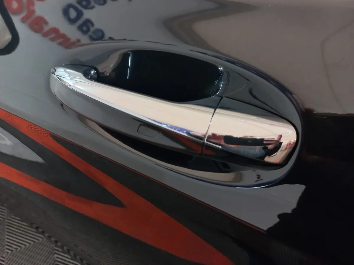 Poignée de porte chromée en gros plan sur la portière noire d'un Mercedes GLC 300 E Business Line 4MATIC hybride rechargeable.