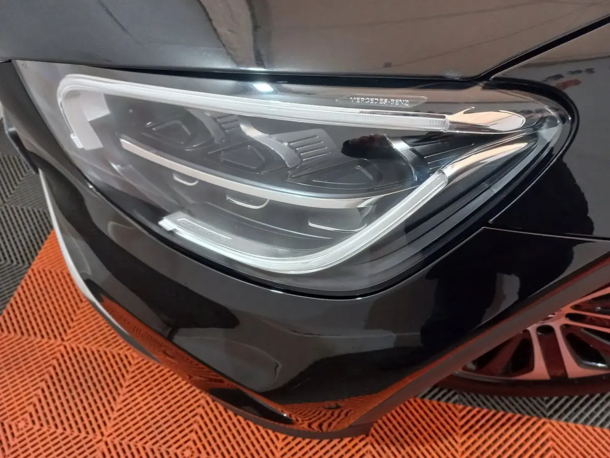 Gros plan sur le phare avant droit noir brillant du Mercedes GLC 300 E Business Line hybride rechargeable.