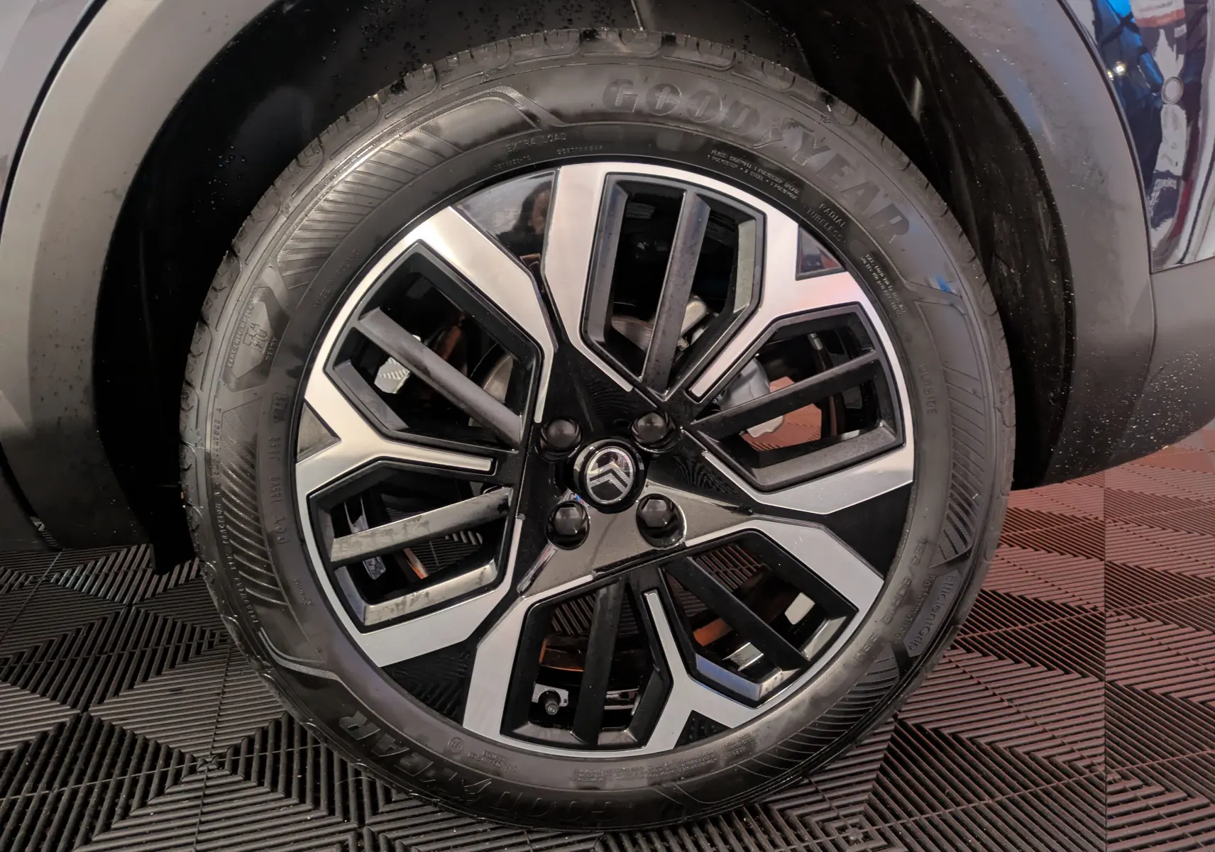 Gros plan sur la jante alliage 18 pouces bicolore du côté avant droit d'une Citroën C4 bleu nuit hybride 2025.