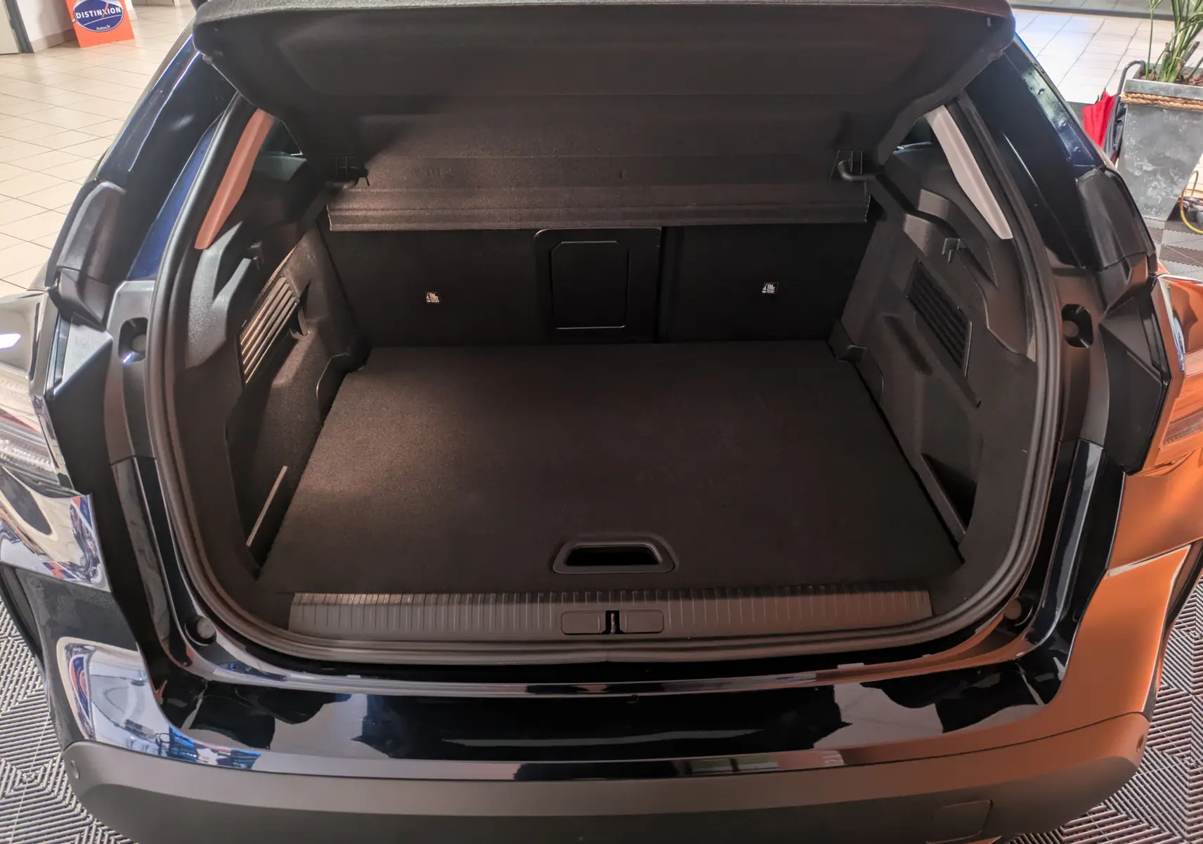 Coffre ouvert vu de l'arrière d'une Citroën C4 hybride 2025 bleu nuit, montrant un espace de chargement spacieux.