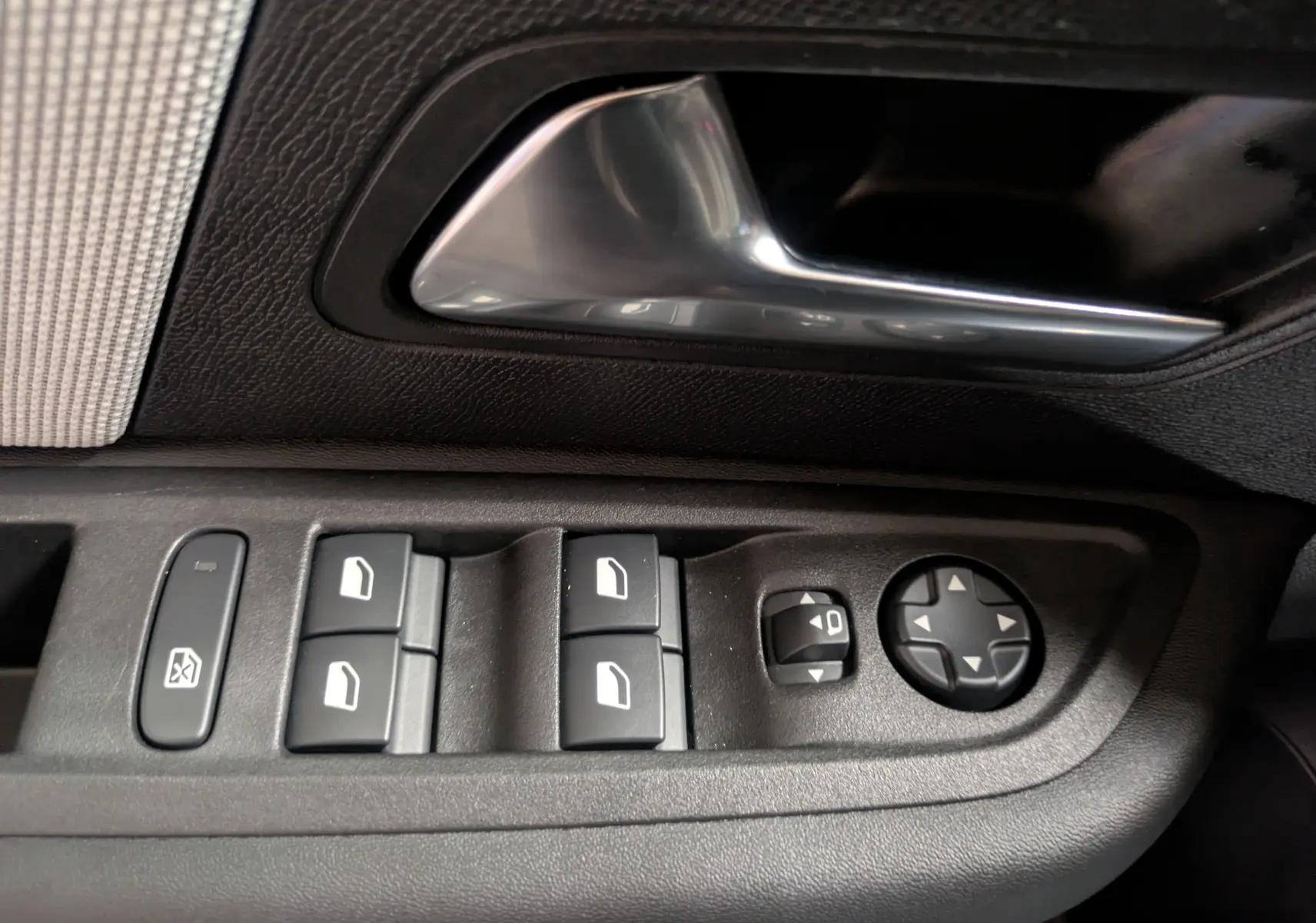 Gros plan sur les commandes de vitres et rétroviseurs côté conducteur d'une Citroën C4 Hybride 145 e-DCS6 Max, intérieur noir.