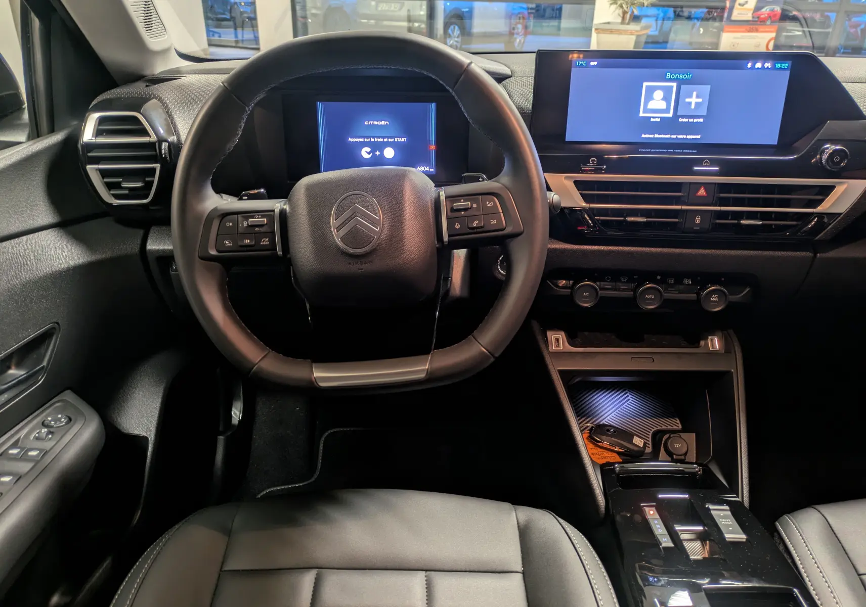 Vue intérieure centrée sur le volant et tableau de bord numérique de la Citroën C4 hybride 2025 avec écran tactile et commandes au volant.
