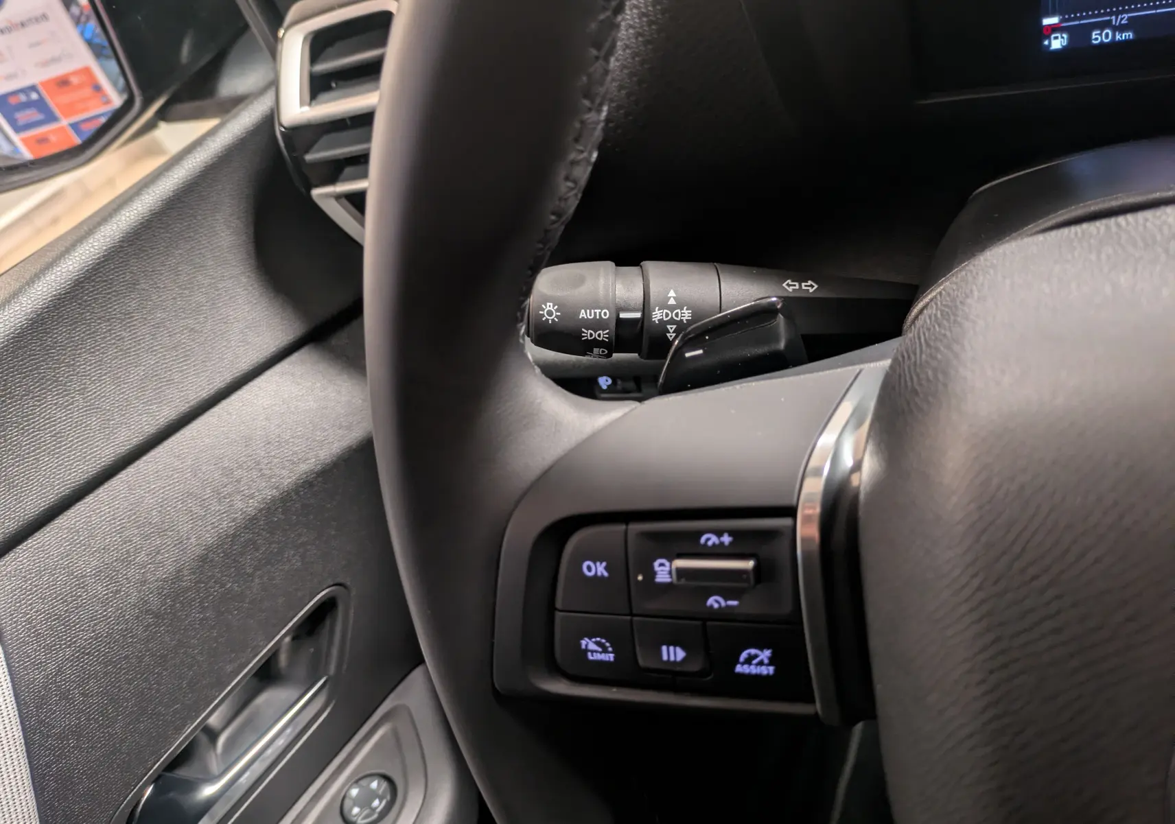 Gros plan sur le volant côté gauche de la Citroën C4 hybride 2025, avec commandes intégrées et levier de clignotant visible.