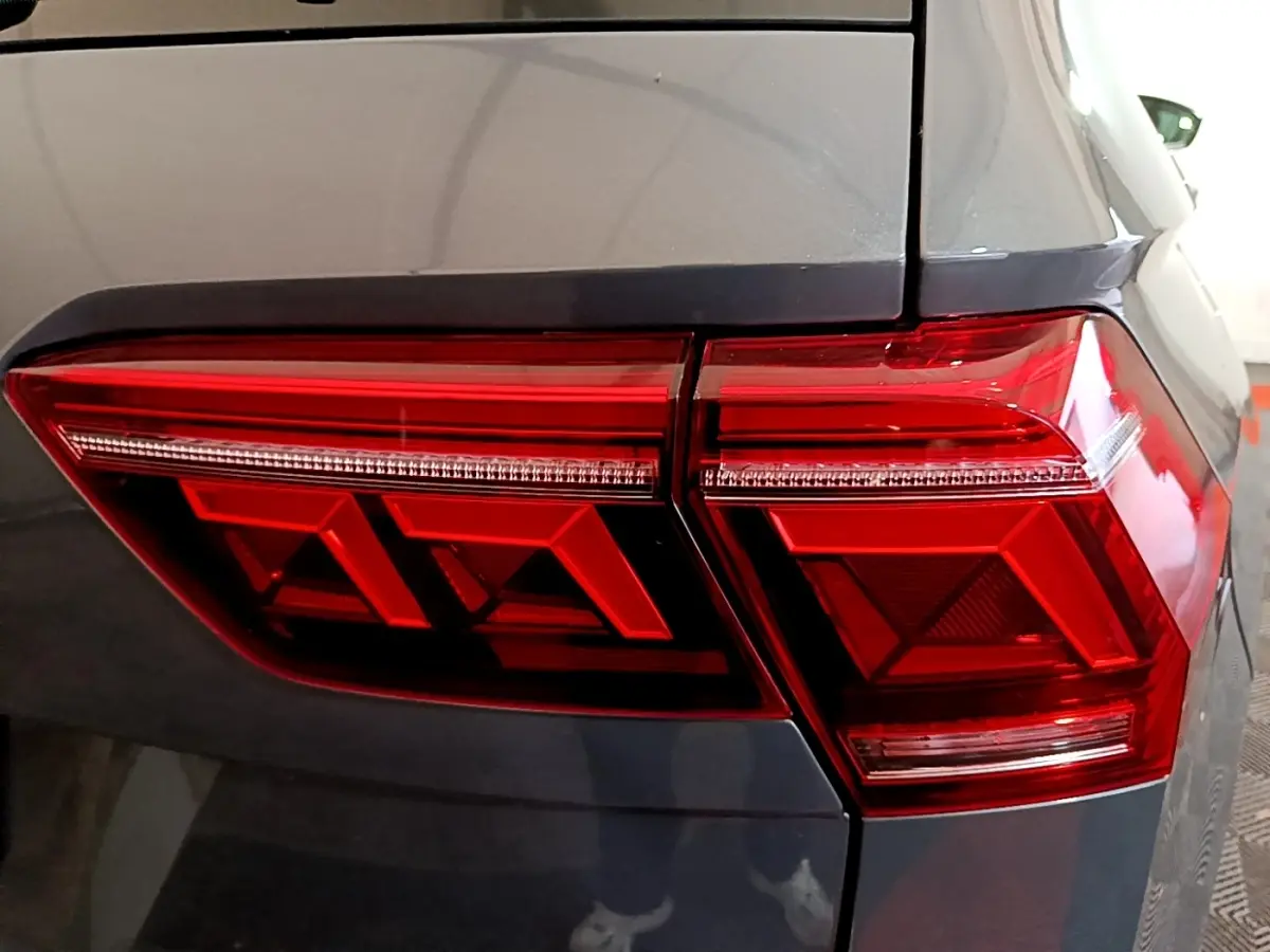 Gros plan sur le feu arrière droit rouge d’un Volkswagen Tiguan gris clair, soulignant ses formes géométriques modernes.