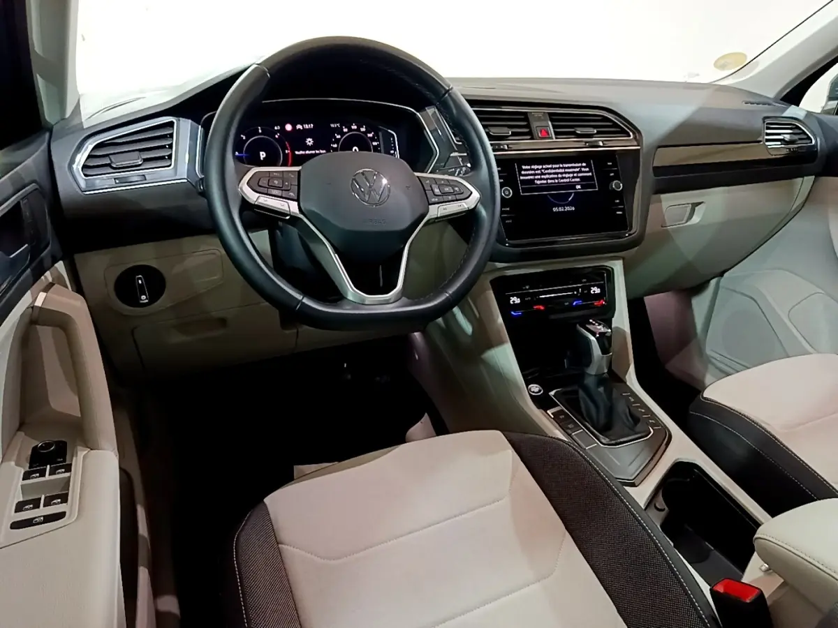 Vue intérieure avant du Volkswagen Tiguan 2.0 TDI gris clair, volant cuir multifonctions et écran tactile central.
