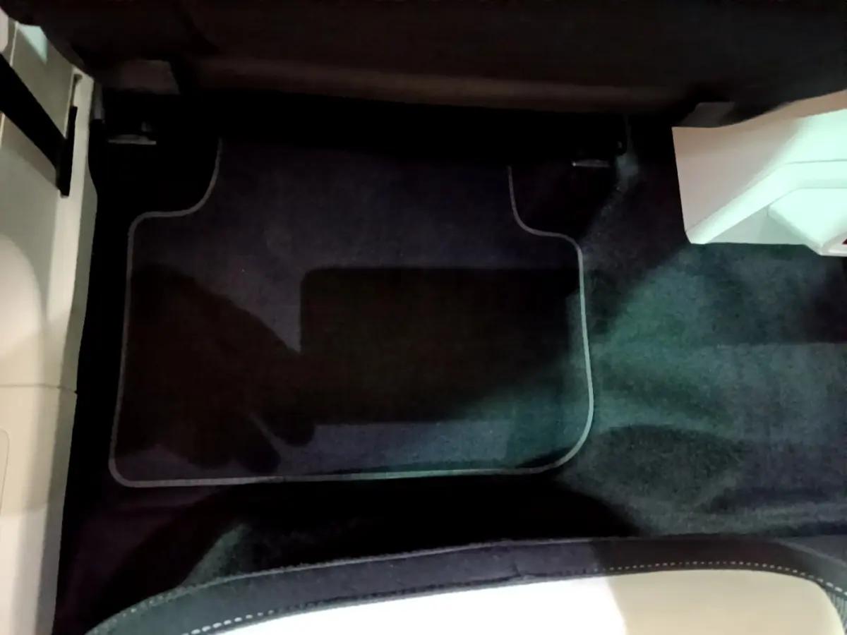 Vue du sol côté passager avant du Volkswagen Tiguan gris clair, avec tapis de sol noir et partie de la console visible.