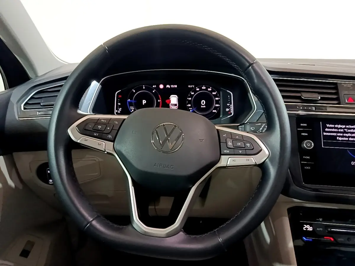 Vue intérieure centrée sur le volant cuir noir et le tableau de bord numérique du Volkswagen Tiguan 2022.