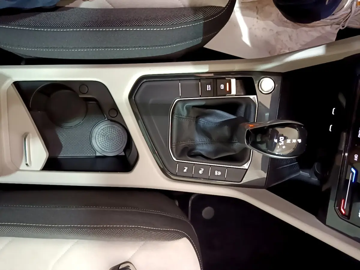 Vue plongeante sur la console centrale beige et noire du Volkswagen Tiguan 2.0 TDI 150 DSG7 avec levier de vitesse automatique.