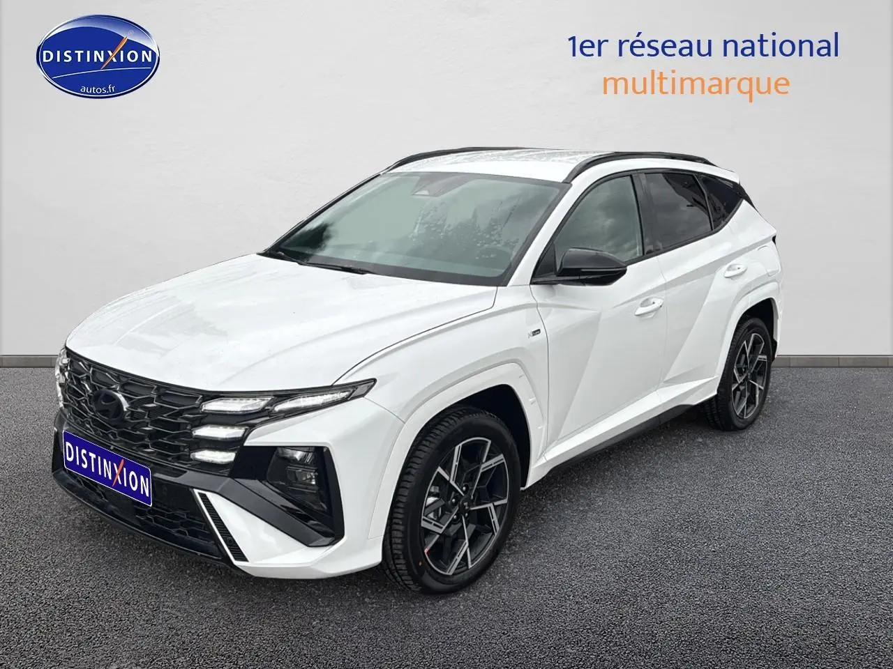 Vue 3/4 avant droite d'un Hyundai Tucson blanc sérénité avec calandre noire et jantes alliage 19 pouces.