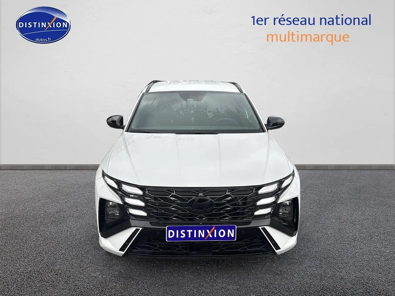 Vue frontale du Hyundai Tucson blanc sérénité avec calandre noire et feux LED distinctifs en ligne.