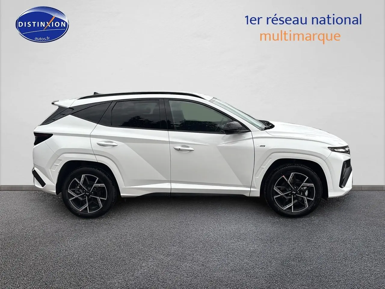 Vue de profil côté gauche du Hyundai Tucson blanc sérénité avec jantes alliage noires et toit panoramique.