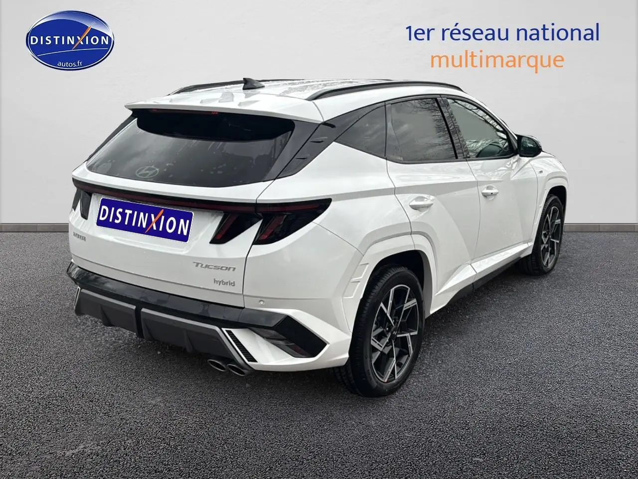 Vue 3/4 arrière droite d'un Hyundai Tucson blanc sérénité avec jantes alliage 19 et détails N Line noirs.