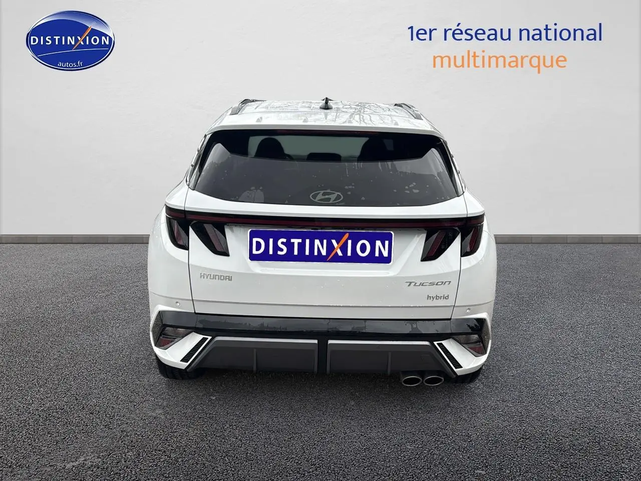 Vue arrière d'un Hyundai Tucson blanc sérénité hybride avec feux LED et double sortie d'échappement à droite.