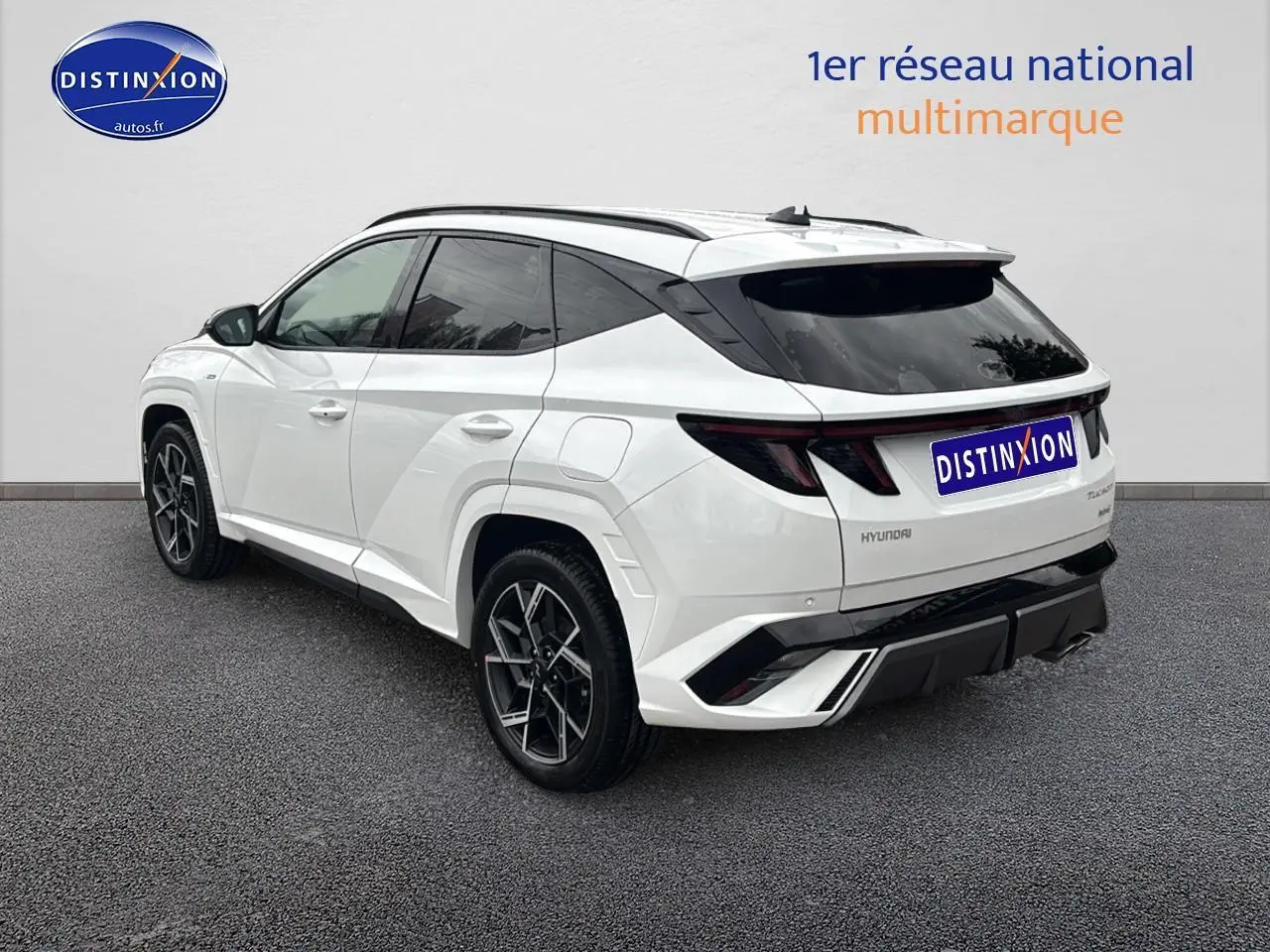 Vue 3/4 arrière droite d'un Hyundai Tucson blanc sérénité avec jantes alliage 19 et détails noirs N Line.