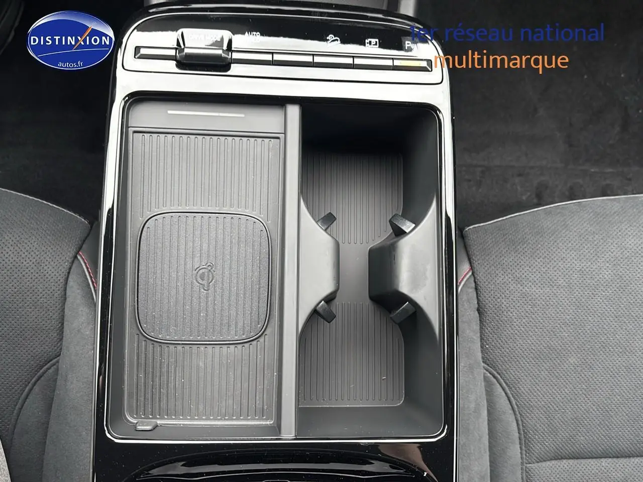 Vue plongeante sur la console centrale noire du Hyundai Tucson 2026 avec compartiments et porte-gobelets visibles.