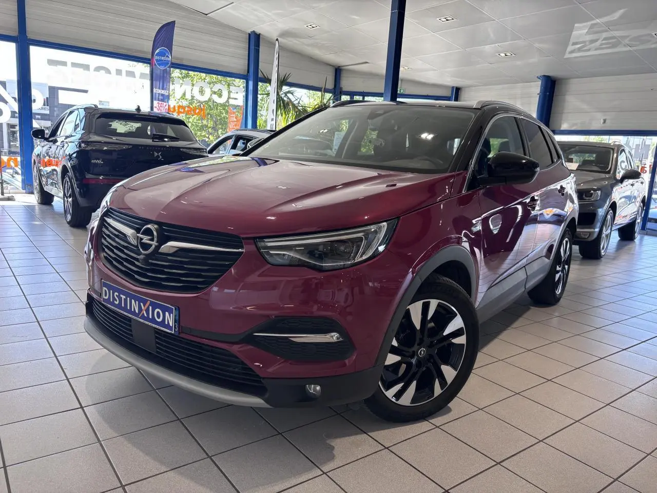 Opel Grandland rouge foncé en 3/4 avant droit, avec jantes alliage noires et toit noir en concession.