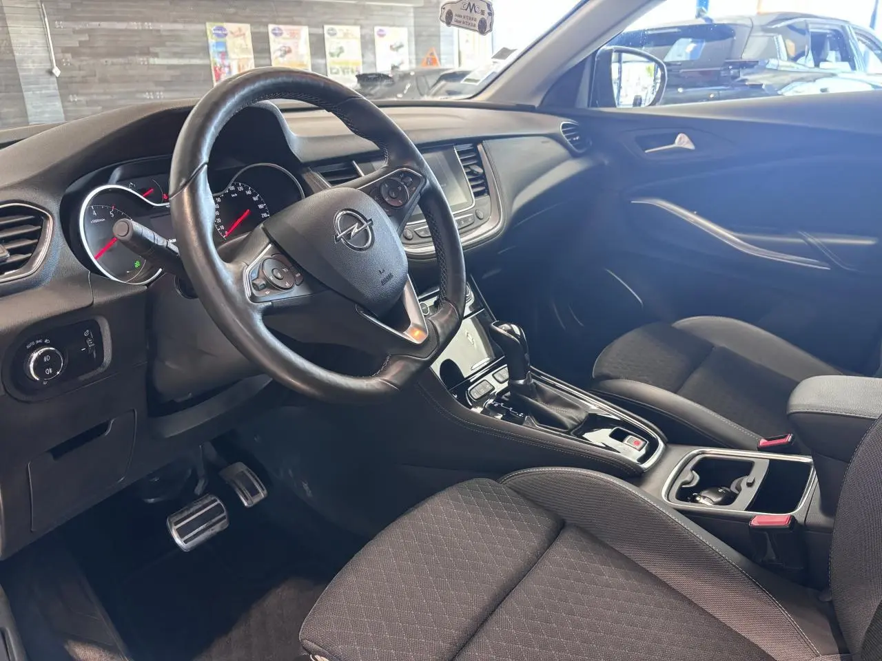 Intérieur avant d’un Opel Grandland 2019, vue côté conducteur montrant volant cuir multifonction et console centrale noire.