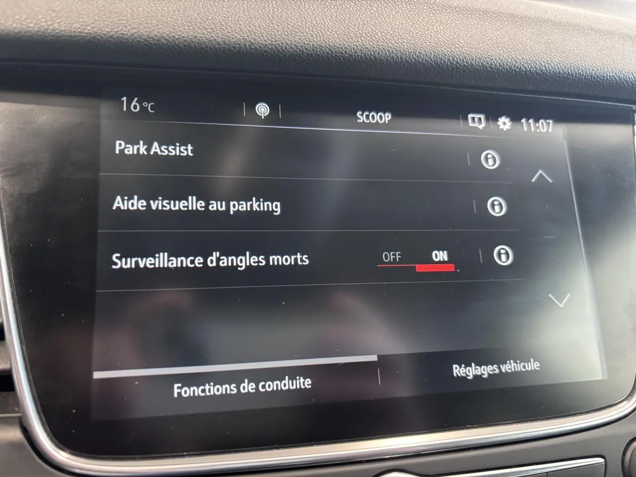 Écran tactile intérieur de l’Opel Grandland rouge foncé affichant les options d’aide au stationnement et surveillance d’angles morts.